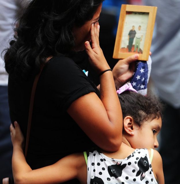 A young girl holds her mother during a commemoration ceremony for the victims of the September 11 terrorist attacks at the National September 11 Memorial and Museum fifteen years after the day on September 11, 2016 in New York