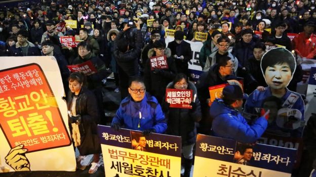 South Koreans march carrying placards reading 