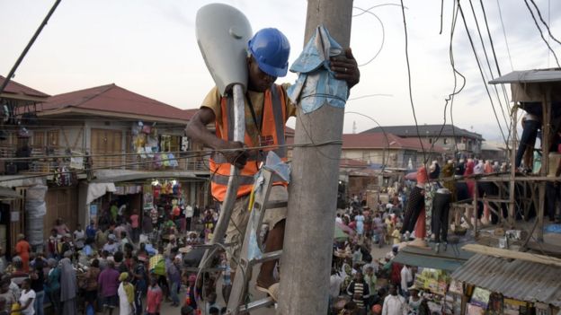 A volunteer of the Bode Edun Foundation sets up a street lamp in the market area of the Oshodi district in Lagos, on June 6, 2015.