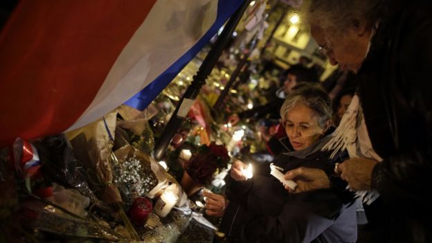Women light candles in front of a memorial set up outside the La Casa Nostra restaurant