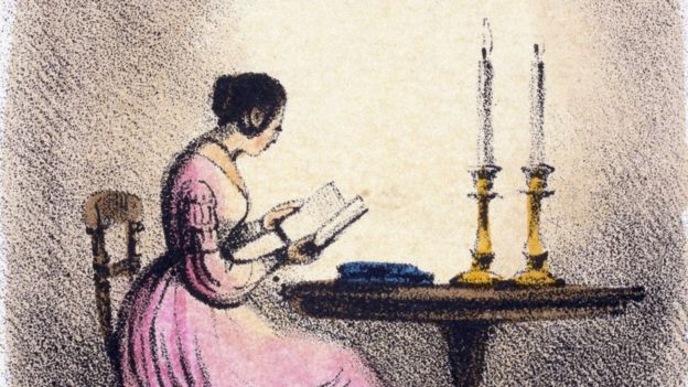 Mujer leyendo a la luz de las velas