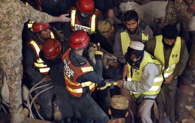 Pakistani rescuers remove a victim from the rubble of a collapsed factory on the outskirts of Lahore on November 4, 2015.