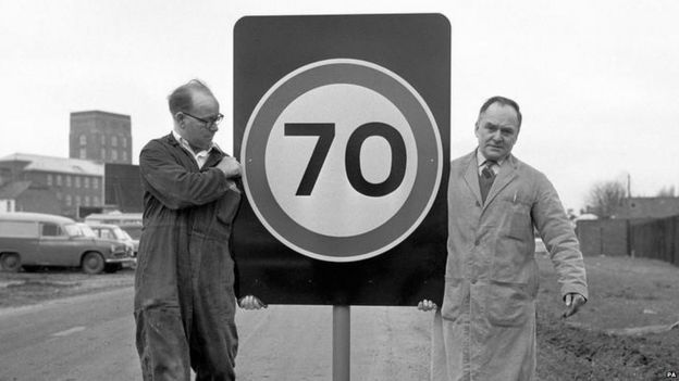 Workmen carrying 70 miles per hour sign in 1965