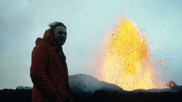 Homem posa ao lado de erupção vulcânica