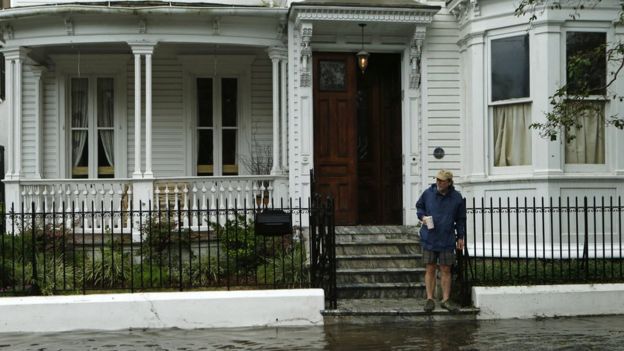 A resident stops short of a flooded pavement as he stands at the edge of steps in Charleston, 8 October 2016