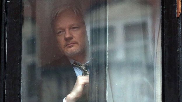 Julian Assange looks out a window of the Ecuadorian embassy in London.