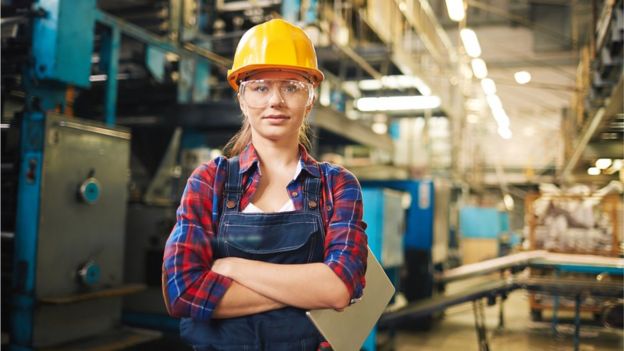 Mujer ingeniera con un casco en una fábrica