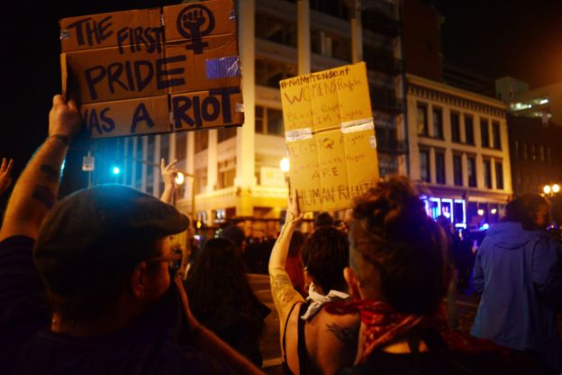 Demonstrators hold up placards during a protest against Donald Trump