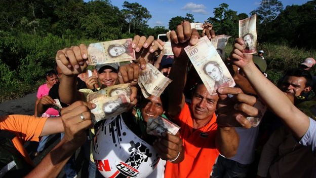 Pessoas com cédulas de 100 bolívares