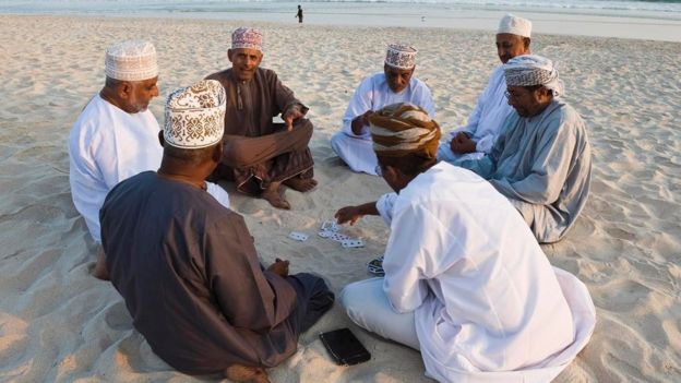 Un grupo de habitantes de Omán jugando cartas en una playa