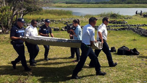 Police carry a piece of debris from an unidentified aircraft found on the French Indian Ocean island of Reunion