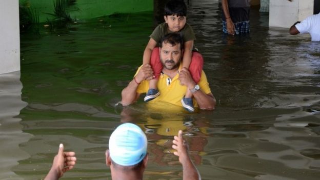 Indian rescuers carry a child to a truck as they evacuate people from a flooded residential area in Chennai on November 17, 2015.