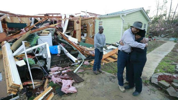 Two people hug near their home wrecked by a storm in the US
