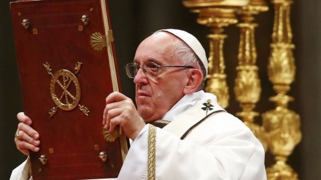 Pope Francis holds the book of the gospels as he leads the Christmas night Mass in Saint Peter's Basilica at the Vatican December 24, 2016
