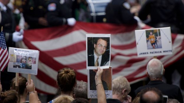 People hold up photos of victims during a memorial service at the 9/11 memorial on in New York.