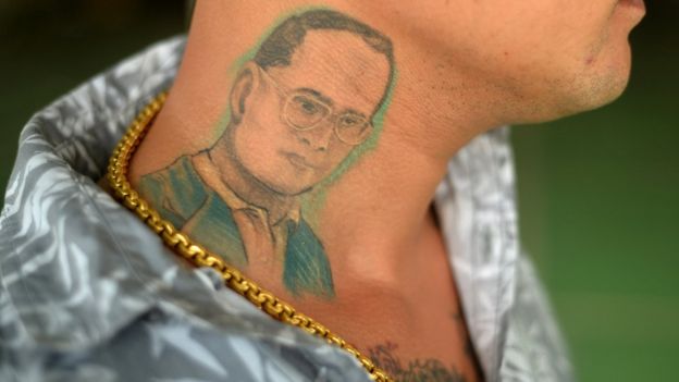 A man poses for a photograph to show his tattoo of Thailand