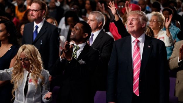 Republican presidential candidate Donald Trump, right, stands and listens during a church service at Great Faith Ministries, Saturday, Sept. 3, 2016, in Detroit.