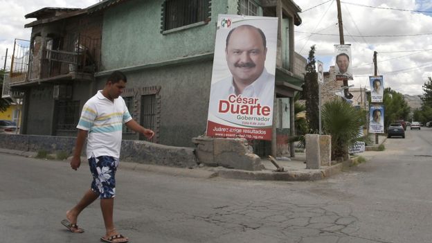 Un hombre pasa por el frente de un cartel de campaña de César Duarte.