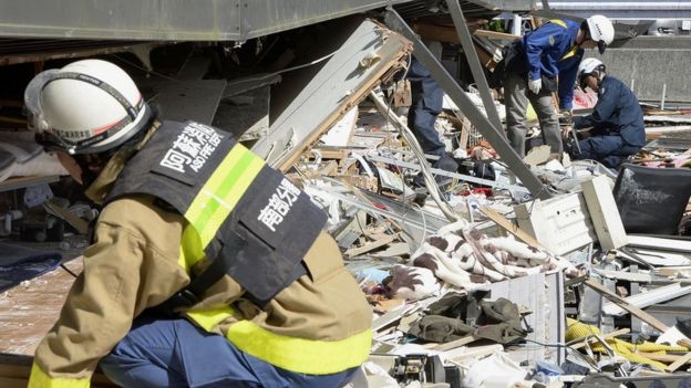 Police and fire fighters try to rescue residents trapped inside an apartment in Minamiaso, Kumamoto prefecture, southern Japan (16 April 2016)