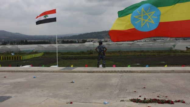 A federal policeman stands guard between the Oromo regional flag (left) and Ethiopia's national flag at the October ceremony marking the opening of the Addis Ababa-Djibouti railway