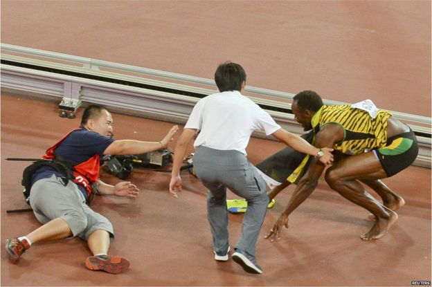 Usain Bolt of Jamaica (R) gets up after being knocked over by a cameraman (L) on a Segway as he celebrates after winning the mens 200 metres final during the 15th IAAF World Championships at the National Stadium in Beijing, China, 27 August 2015