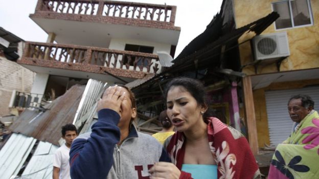 A woman weeps outside a house destroyed in Ecuador's earthquake
