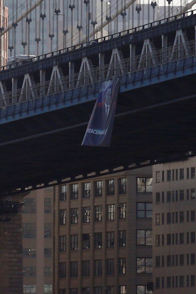 A photo of the banner showing Putin wearing a suit, in front of the Russian flag, with the word 'peacemaker'