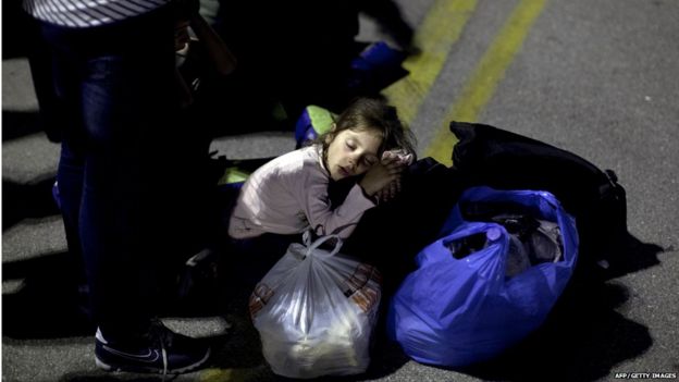 A migrant child sleeps as she waits to board a bus after disembarking from a ferry at the port of Piraeus in Athens on September 1, 2015