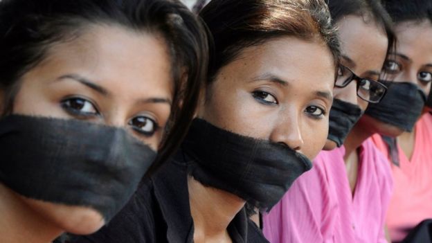 Miembros de una asociación de fotoperiodistas con bandas negras en la boca, protestan por la violación de una colega.