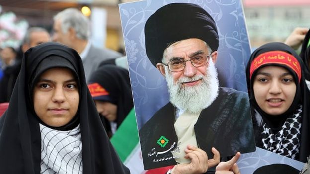 Iranian women hold posters of Iran's Supreme Leader Ayatollah Ali Khamenei durring a rally in Tehran to mark the 36th anniversary of the Islamic revolution in February 2015