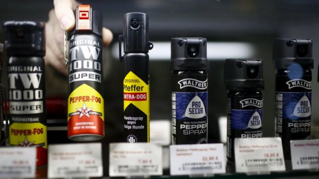 A shop assistant sets up a row of pepper spray in a showcase of a gunsmith's shop in Berlin