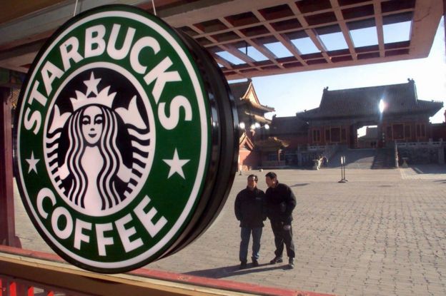 Two Chinese tourists look 10 November 2000 at a Starbucks coffee shop which has opened in the heart of Beijing's historic Forbidden City, once the exclusive preserve of China's emperors.