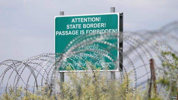 A warning sign is pictured behind a barbed wire barricade erected by Russian and Ossetian troops along Georgia's de-facto border with its breakaway region of South Ossetia, 14 July 2015