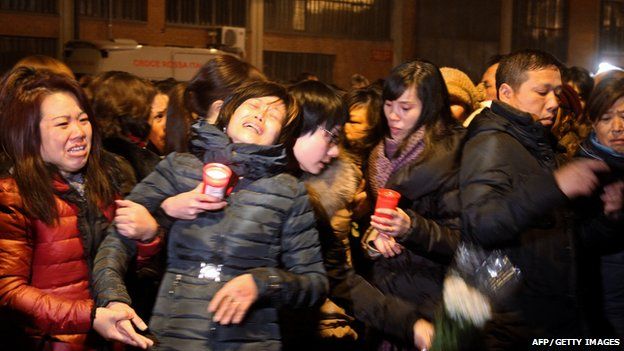 Chinese people cry and hold candles late on December 3, 2013 in Prato in homage to the seven victims of a Chinese-run garment factory fire