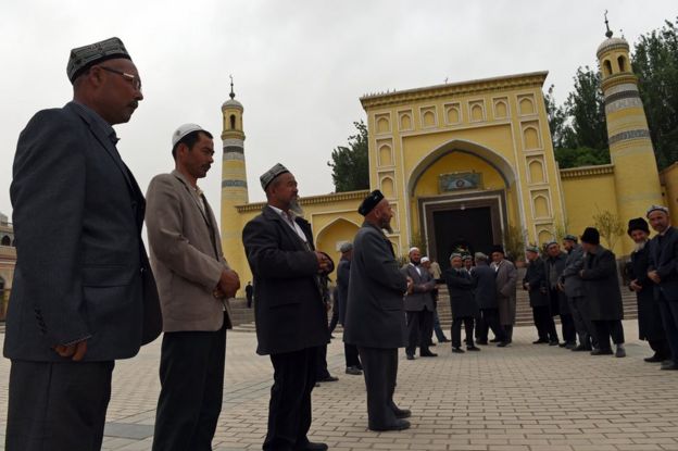 This photo taken on 19 April 2015 shows Uighur men gathering outside for afternoon prayers at the Id Kah mosque in Kashgar, in China's western Xinjiang region