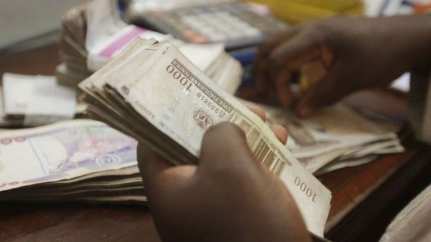 a money changer counts Nigerian Naira currency