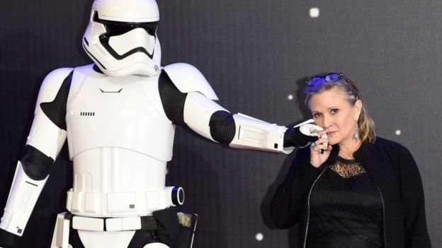 Carrie Fisher poses next to a Stormtrooper at a film premier