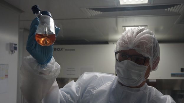 A scientist at INstituto D'Or holds up a bottle with liquid