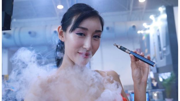 A model smokes an e-cigarette during the Beijing International Vapor Distribution Alliance Expo
