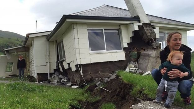 A woman and child in front of a house damaged by an earthquake as it sits on the fault line at Bluff Station near Kaikoura (14 November 2016)