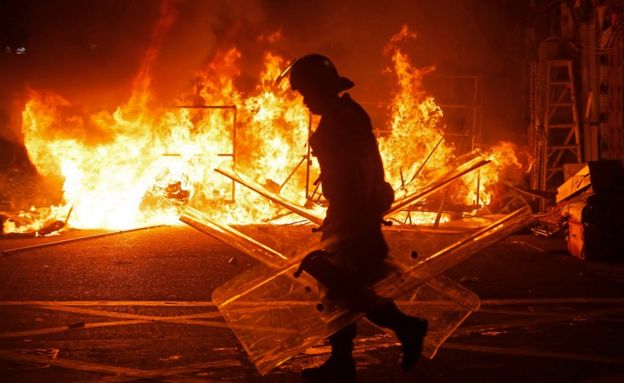 A police officer walks past a fire burning at barricades