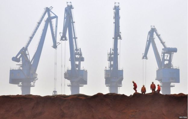 Workers remove the cloth covering iron ore waiting to be transported at a port in Tianjin municipality in this 29 March 2010 file picture