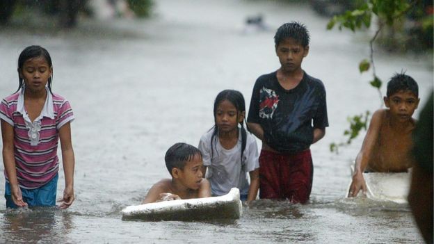 Children wade through floodwaters in the Philippines