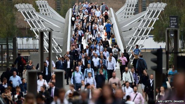 Commuters cross the river Thames on the Millennium footbridge during rush hour