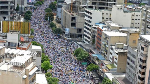 Una multitud camina por una gran avenida en Caracas.