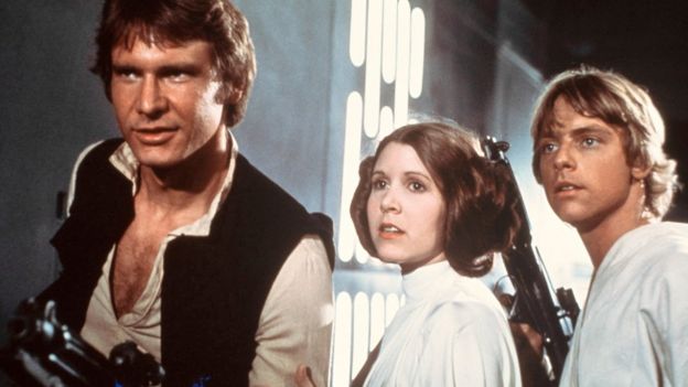 Carrie Fisher (C), with Harrison Ford (L) and Mark Hamill in the first Star Wars film