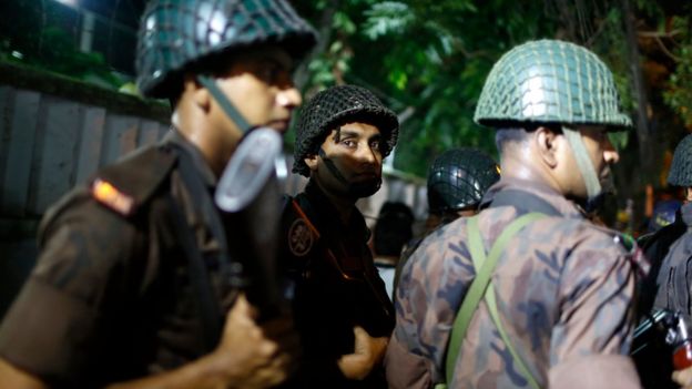 Bangladeshi security personnel stand guard near a restaurant that has reportedly been attacked by unidentified gunmen in Dhaka, Bangladesh, on 1 July