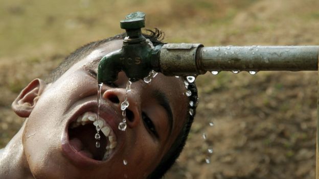 Niño en India tomando agua del grifo