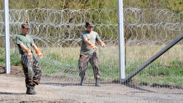 Hungarian soldiers roll out barbed wire