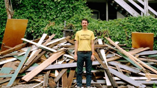 Una persona parada frente a los escombros de una casa